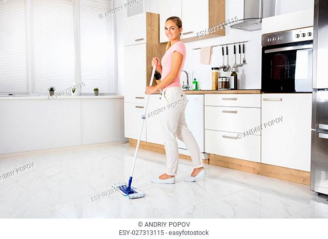 Smiling Cleaning Service Woman With Mop Cleaning Floor In The Kitchen At Home