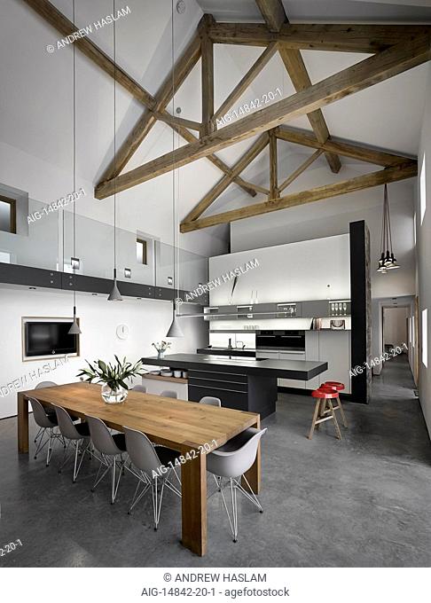 Wooden dining table and black modern island unit in large, open plan, high ceilinged kitchen/dining room, Cat Hill Barn, South Yorkshire, England, UK