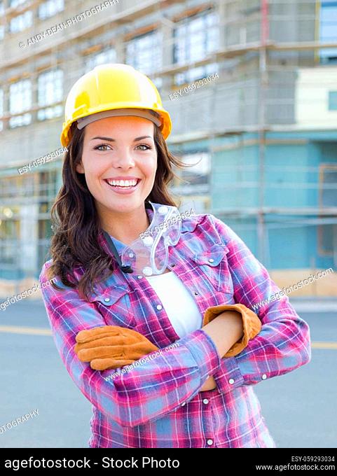 Portrait of Young Attractive Female Construction Worker Wearing Gloves, Hard Hat and Protective Goggles at Construction Site