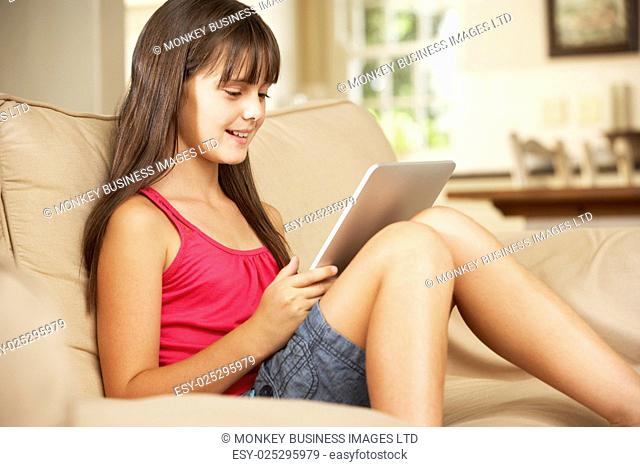 Young Girl Sitting On Sofa At Home Using Tablet Computer