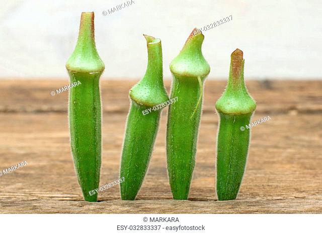 four okra standing on a wooden table background