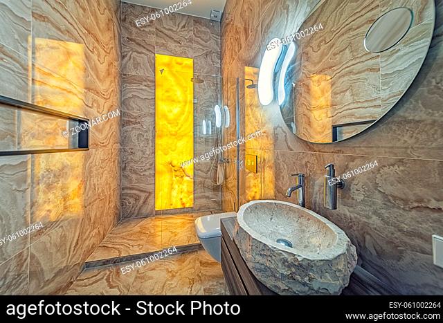 Elegant bathroom in precious natural onyx with rock sink and mirror
