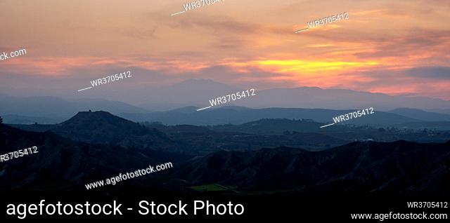 Sunset over the mountains with dramatic clouds. Panoramic mountain landscape at dusk