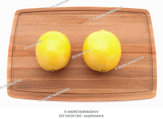 two yellow bright juicy lemon on a wooden board top view