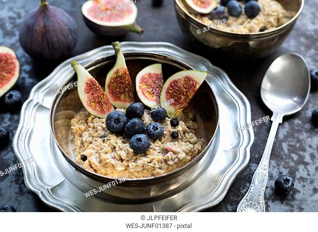 Bowl of porridge with sliced fig, blueberries and dried berries