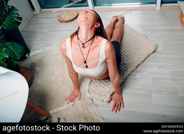 Adult mature woman doing yoga at home living room