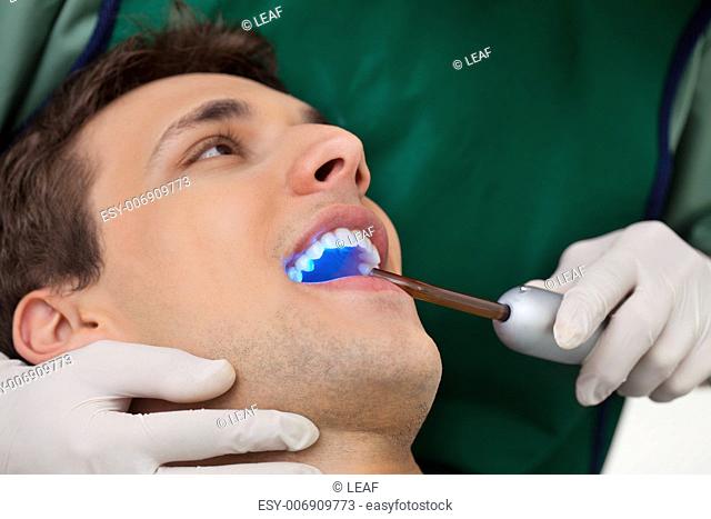 Patient having dental checkup with ultraviolet light at dentist's clinic