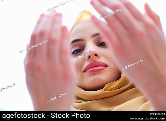 beautiful muslim woman in fashionable dress with hijab making traditional prayer to God, keeps hands in praying gesture isolated on white background...