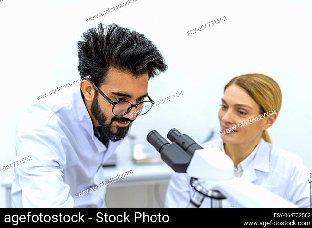 Modern Medical Research Laboratory. Scientists using microscope, doing sample analysis, talking, team of specialists work in lab with biochemistry or...