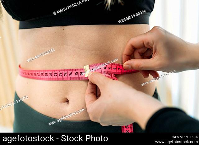 Measuring waist of sportswoman with tape measure