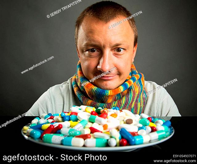 Surprised man looking on plate full of pills and capsules
