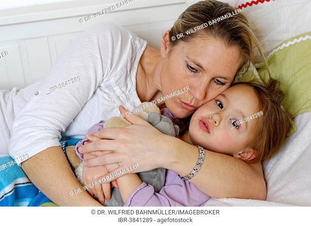 Mother and daughter cuddling in bed, hugging