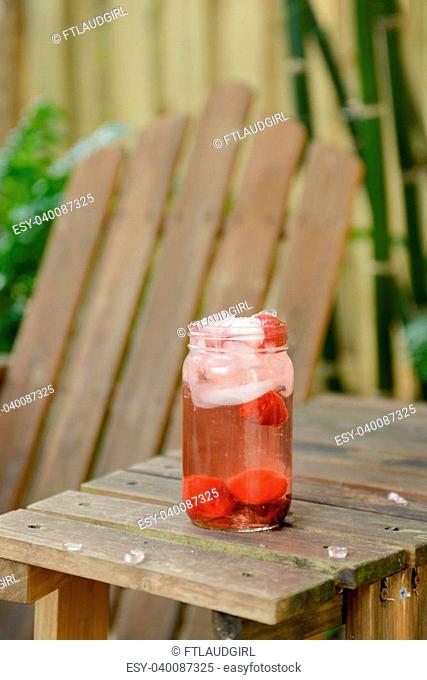 summer drink in mason jar outside with strawberries