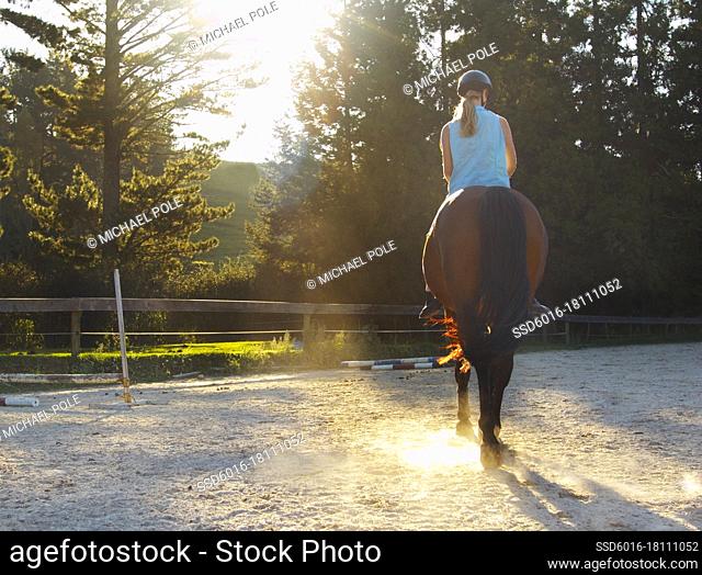 Teenage girl riding horse bareback - back view