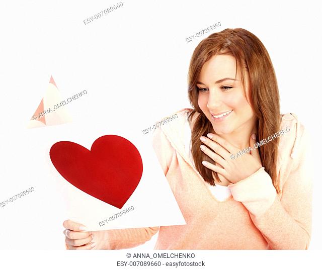 Image of happy beautiful female reading romantic greeting card with big red heart, attractive brunette woman got love letter