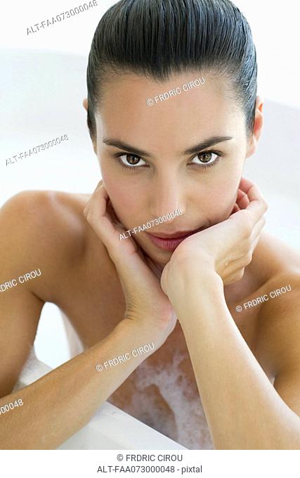 Woman in bath, leaning against edge of bathtub