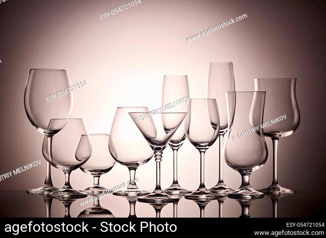 Set of glasses for different alcoholic drinks and cocktails on dark gray background. Empty clear glassware