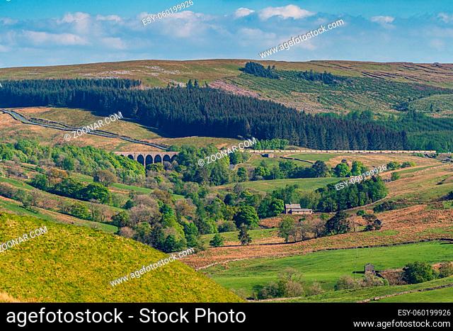 Near Cowgill, Cumbria, England, UK - May 16, 2019: A train passing the Dent Head Viaduct on the Settle-Carlisle Railway line