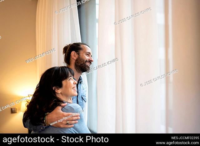 Happy couple looking away in hotel suite