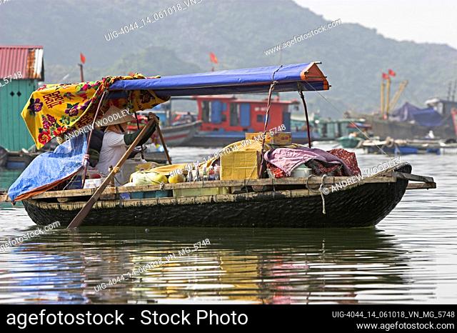 Woman selling food fruit and drinks from floating shop rows around the fishing village in Cat Ba Town bay north east Vietnam