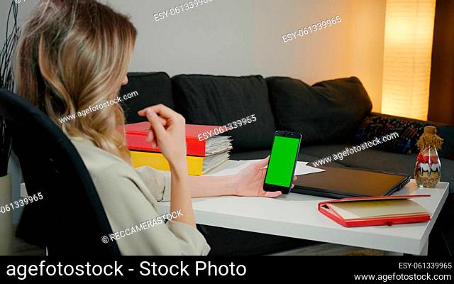 Back View of Woman at Phone with Green Screen for Copy Space. Chromakey Mockup. Talks on the phone, gesturing with hands