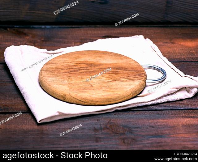 empty round wooden board on a gray napkin, brown background
