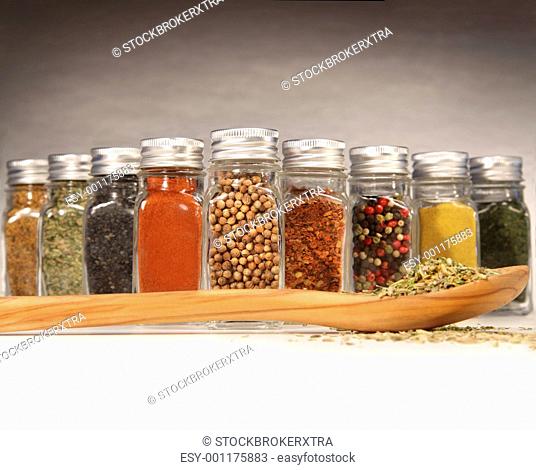 Colorful spices in bottles with wooden spoon