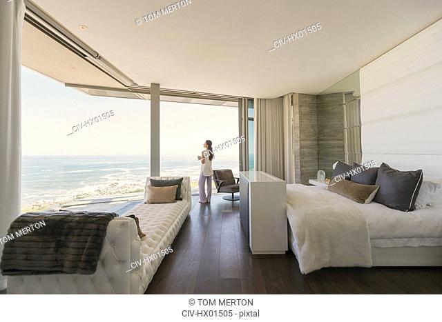 Woman looking at ocean view from modern luxury home showcase bedroom