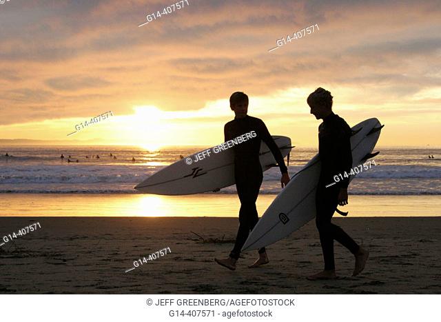 Teen surfers, sunset, waves, clouds. Balboa Peninsula. Newport Beach. California. USA