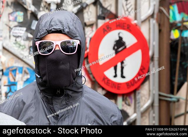 08 October 2021, Berlin: A resident of the ""Köpi"" Wagenplatz stands in front of the entrance gate at the end of a press conference of the left-wing autonomous...