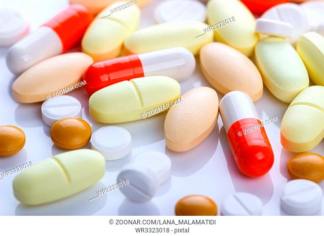 Medical pills and tablets on white reflected background, selective focus, macro shot