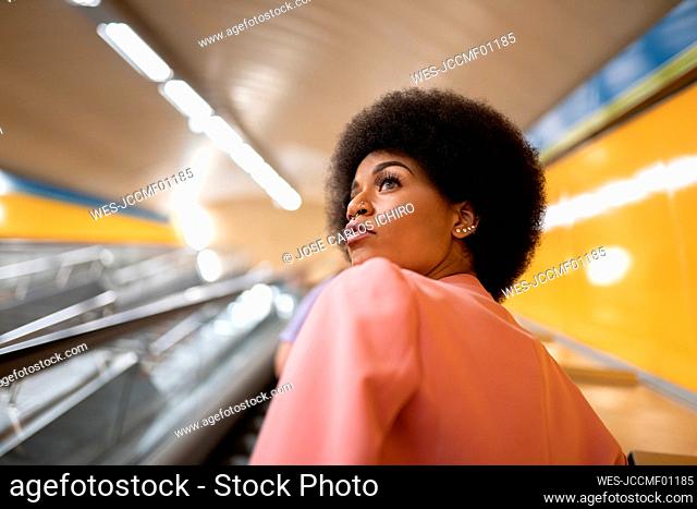 Afro woman on escalator at subway station
