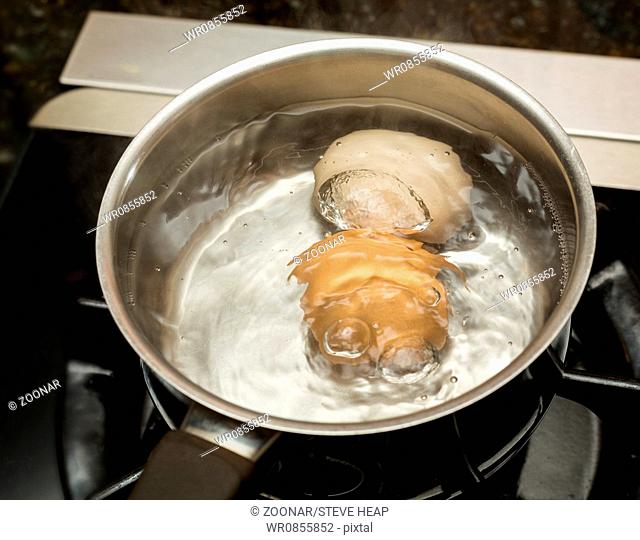 Two boiling eggs in stainless saucepan