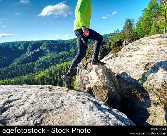 Fitness man trail runner running to rocky mountain top on cracked rocky block