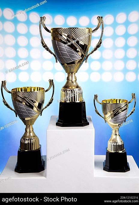 Cups of winners award on white podium, sport background