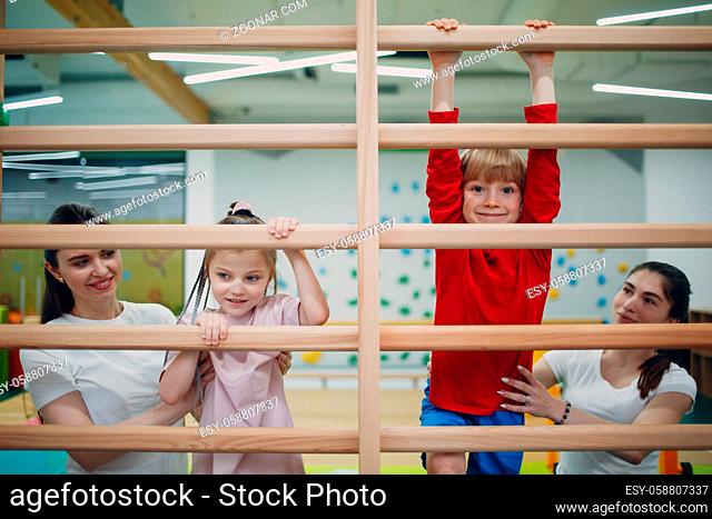 Kids doing Swedish wall exercises in gym at kindergarten or elementary school. Children sport and fitness concept