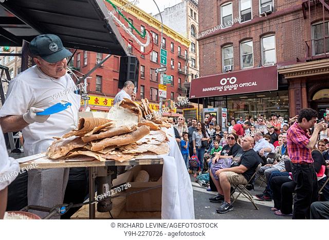 Workers from Ferrara Bakery and Cafe put the finishing touches on their attempt to assemble the world's largest cannolo singular of cannoli at the 88th Annual...