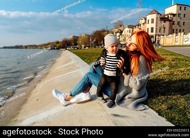 Mother hugging her little son on the bank of the river