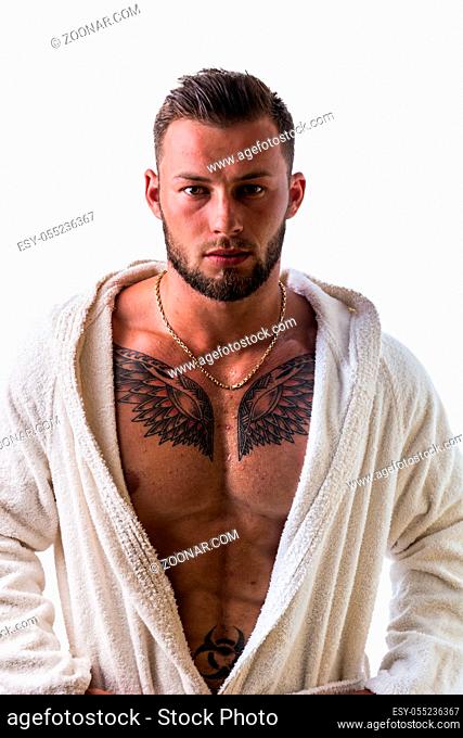 Handsome young muscle man wearing white bathrobe, keeping it open on muscular torso and pecs, isolated on white background