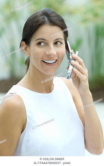 Woman using cell phone, smiling, looking away