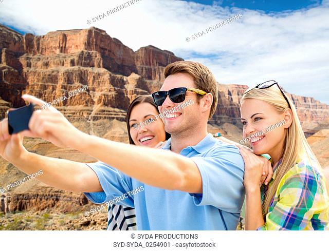 group of happy friends taking selfie by cell phone