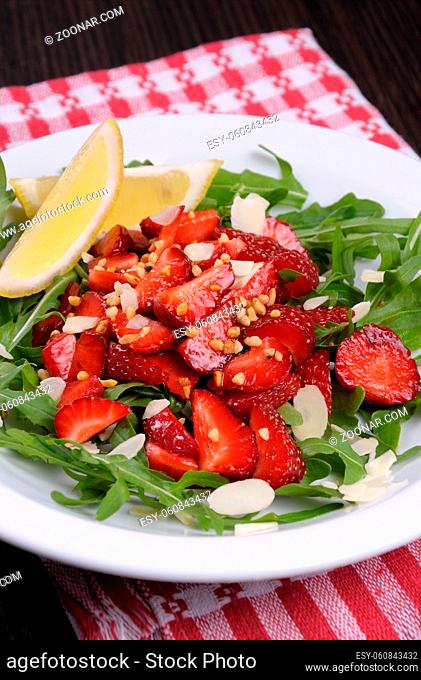 Salad of arugula and strawberries with crushed peanuts, almonds
