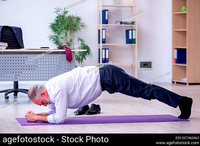 Aged employee doing physical exercises during break
