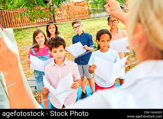 Kinder singen zusammen im Chor im Ferienlager unter Anleitung der Musik Lehrerin