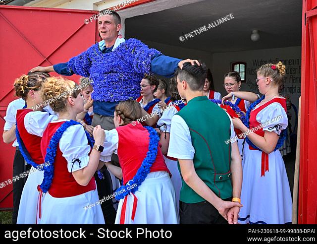 18 June 2023, Brandenburg, Casel: Tobias Richter, who is St. John this year, is decorated with cornflowers by girls. The St