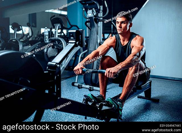 Muscular athlete training press on exercise machine. Active sport exercises in gym