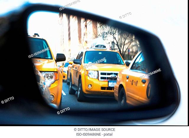 Queue of yellow cabs viewed through wing mirror, New York City, USA