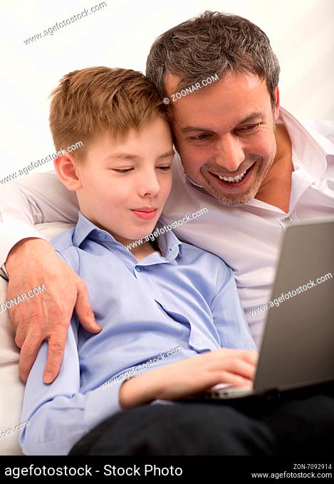 Son and father with laptop at home. They found something interesting and looking at screen