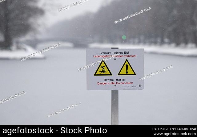 01 December 2023, Bavaria, Munich: A sign with the inscription ""Caution - thin ice! Danger to life! No trespassing!"" can be seen on the Nymphenburg Canal