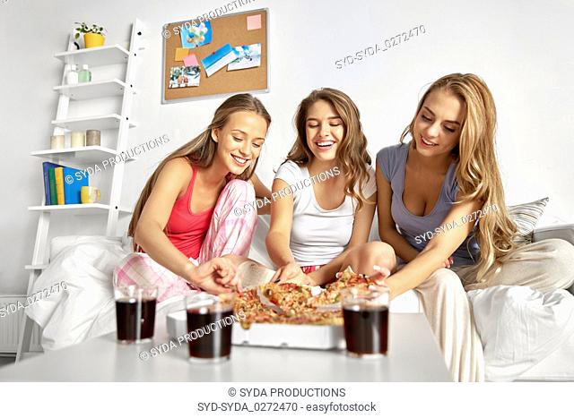 happy friends or teen girls eating pizza at home